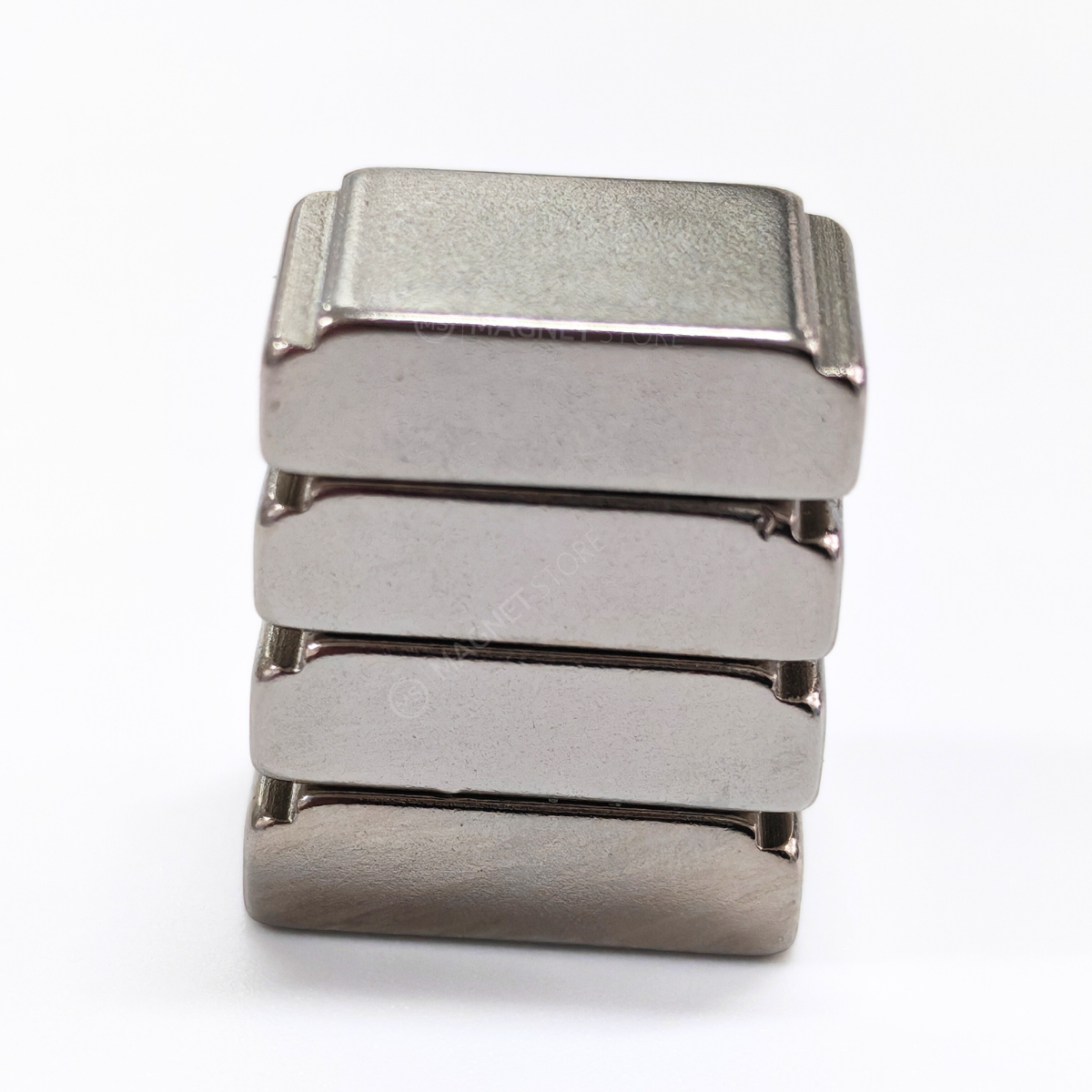 10/7x20x5/4mm N35 Ni Neodymium Step Block Magnet. Rectangular Nickel-coated neodymium magnet with a small step on the top sides. Sold at Magnet Store South Africa, Online and in store. Group of 4 magnets